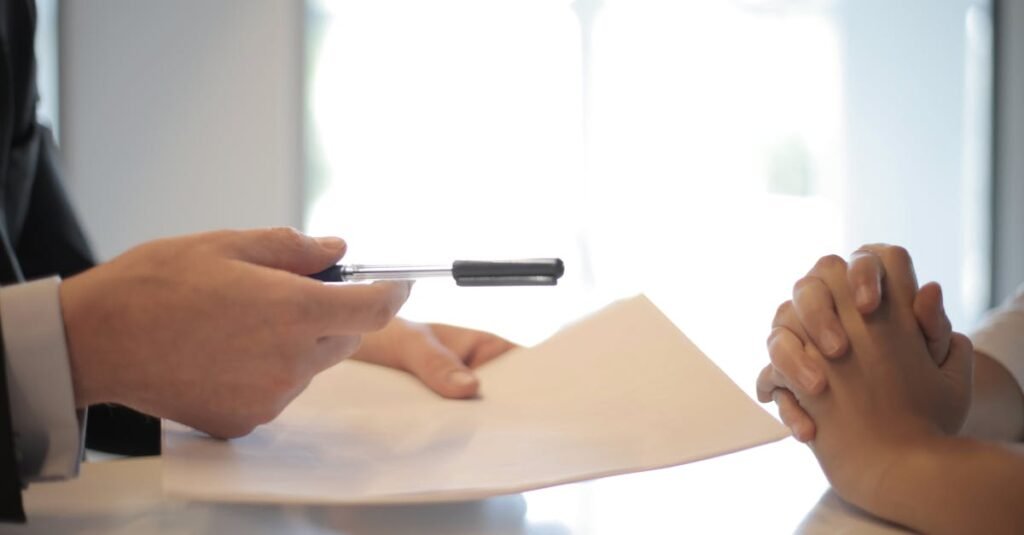 Close-up of a contract signing with hands over documents. Professional business interaction.